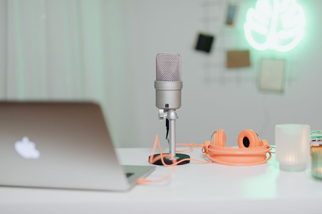 A modern desk setup featuring a condenser microphone, laptop, and headphones in a stylish workspace.
